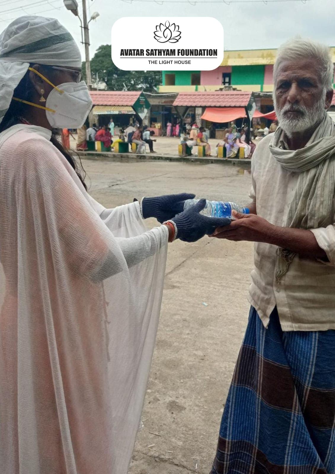 A masked volunteer handing a bottle of drinking water to an elderly man on the street